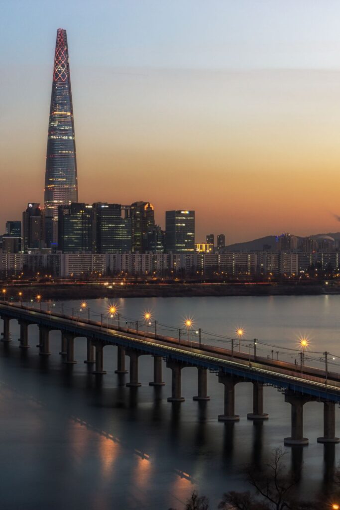 Ultimate Seoul Travel Guide shares must-see attractions like this: The Han River and Lotte World Tower in the distance at sunset.