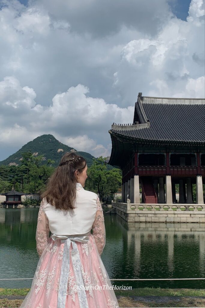A girl travelling in Seoul standing at Gyeongbok Palace, wearing Hanbok - a traditional Korean outfit. Shared on Storm on the Horizon: A travel site for female travellers in the UK, Europe and South Korea.