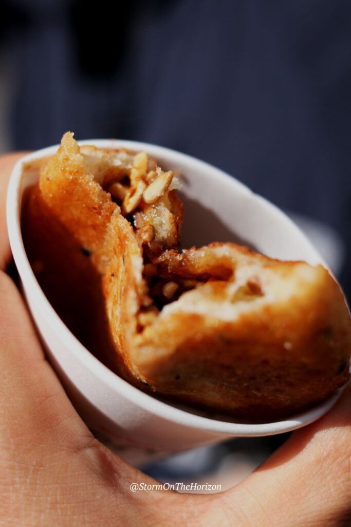 Hotteok (호떡) are a sort of Korean pancake or fritter. They are round and served in a cup. In the image, the inside of the hottoek can be seen: a syrupy sweet centre with nuts and cinnamon. 