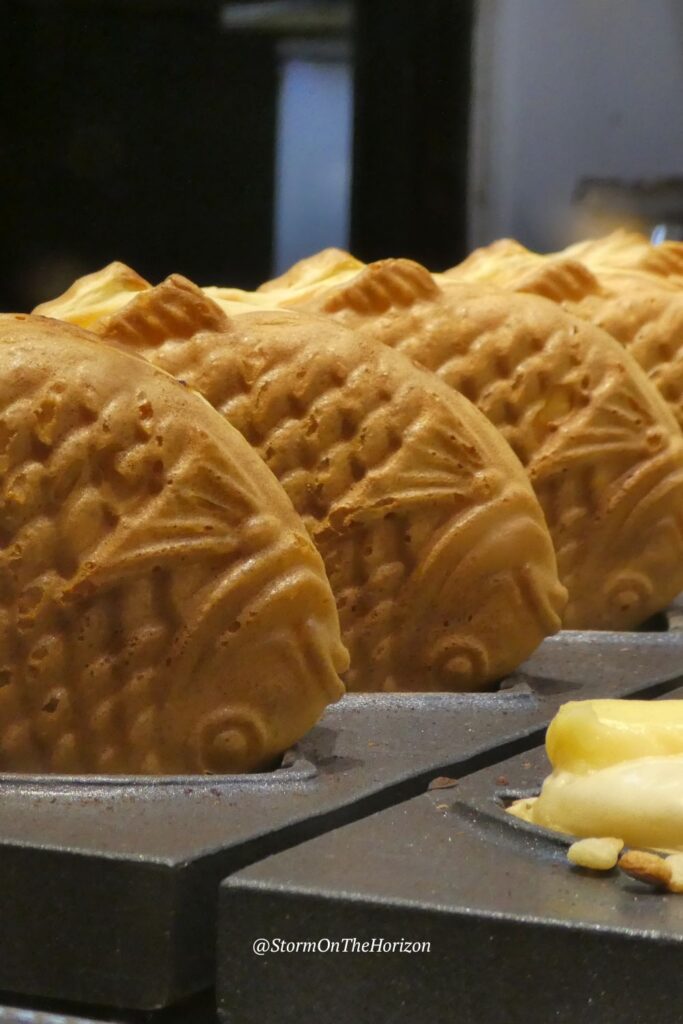 Bungeoppang (붕어빵) are fish-shaped pastries resembling carp. The cute fish pastries are flipped upside down here, standing on their heads as they cool for customers waiting to eat the Korean street food.