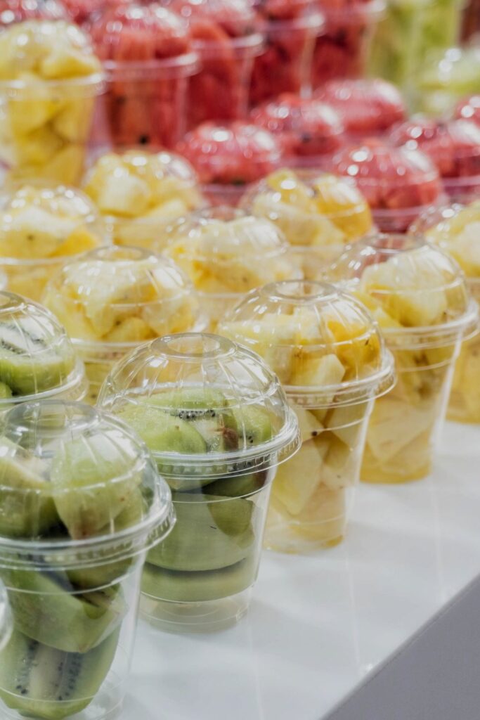 A row of fruit cups sold in South Korea. The plastic cups are filled with an assortment of fruits: Pineapple, kiwi and watermelon which are blended into a smoothie for travellers.